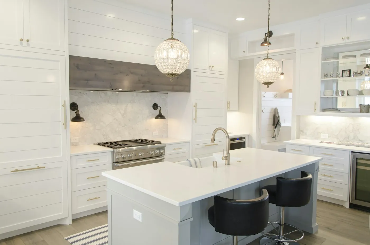 A white kitchen with a large island and glass pendant lights