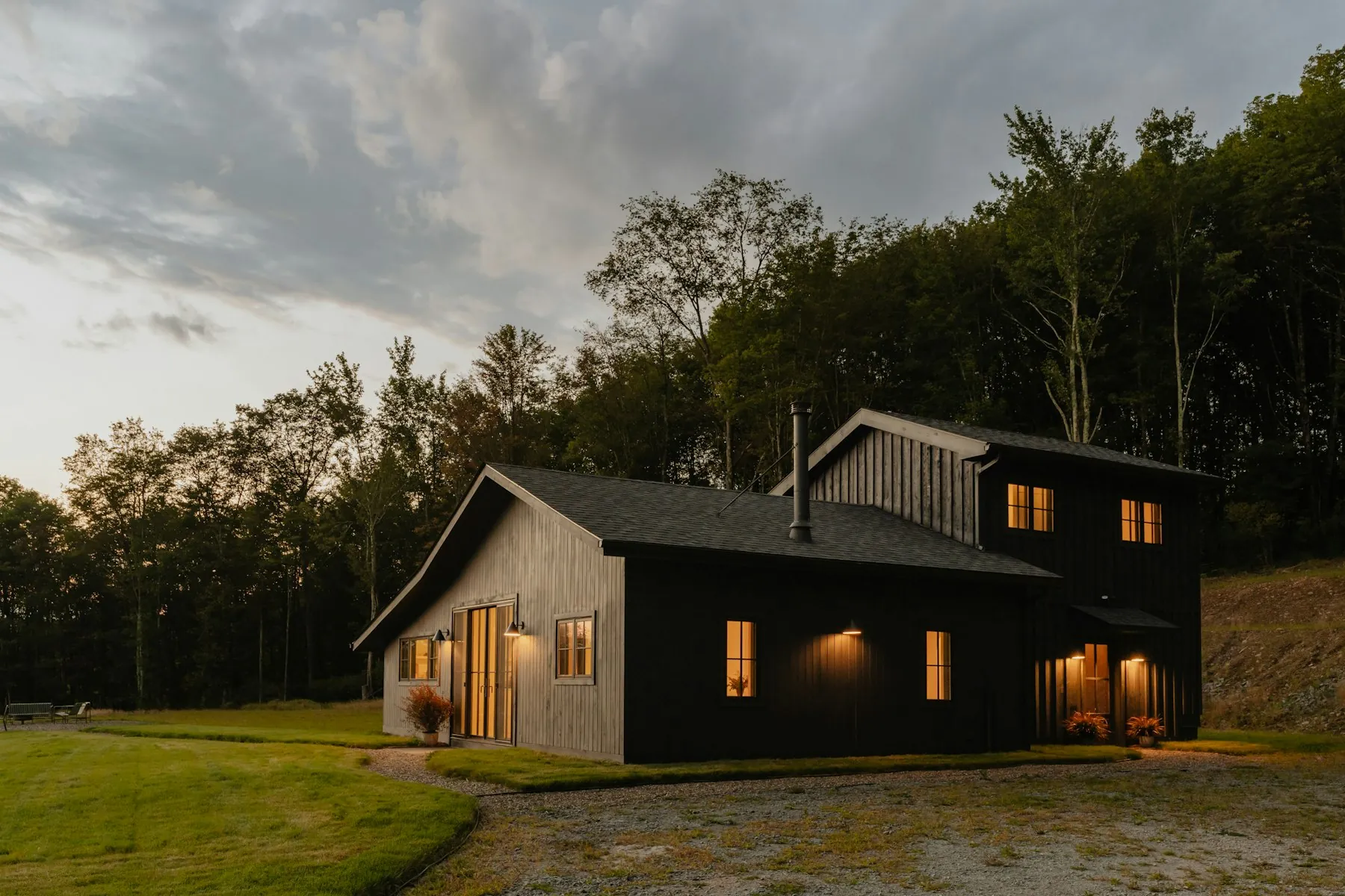 A black-clad farmhouse sitting in a green field under a moody sky